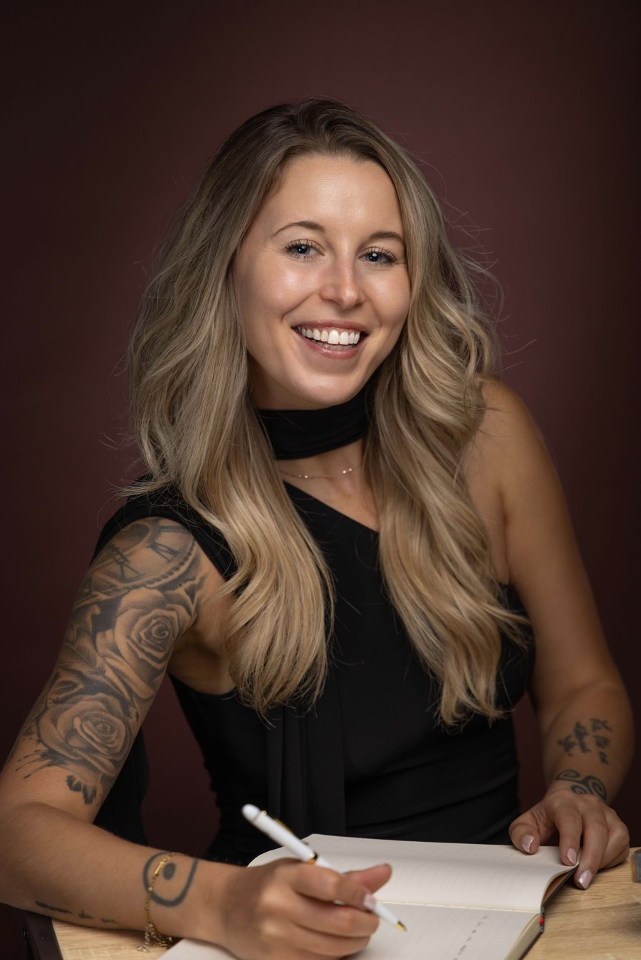Anna Adella, souriante, écrivant dans un carnet